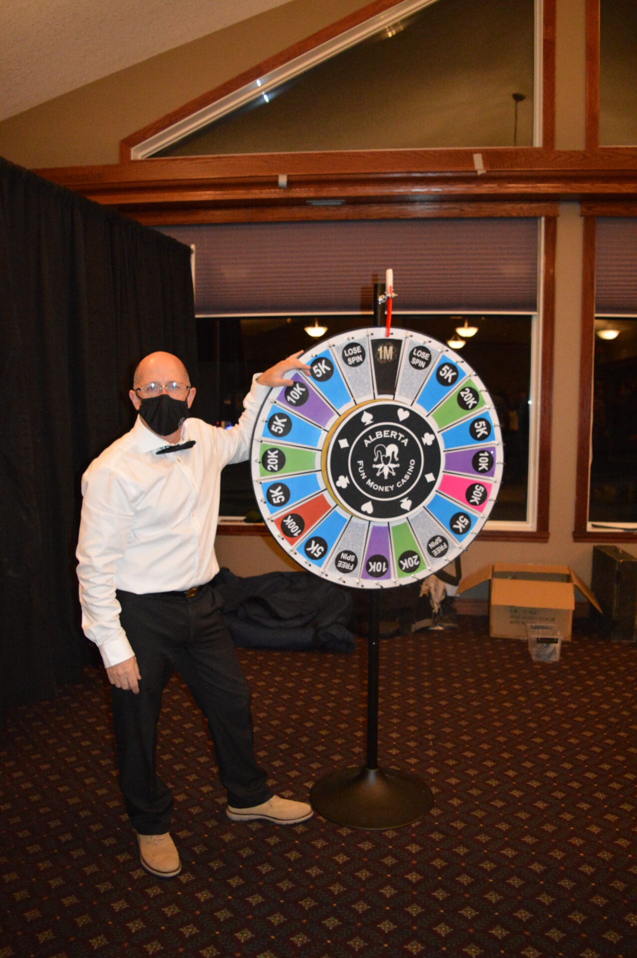 A man in a white shirt and black tie holding a wheel of fortune.