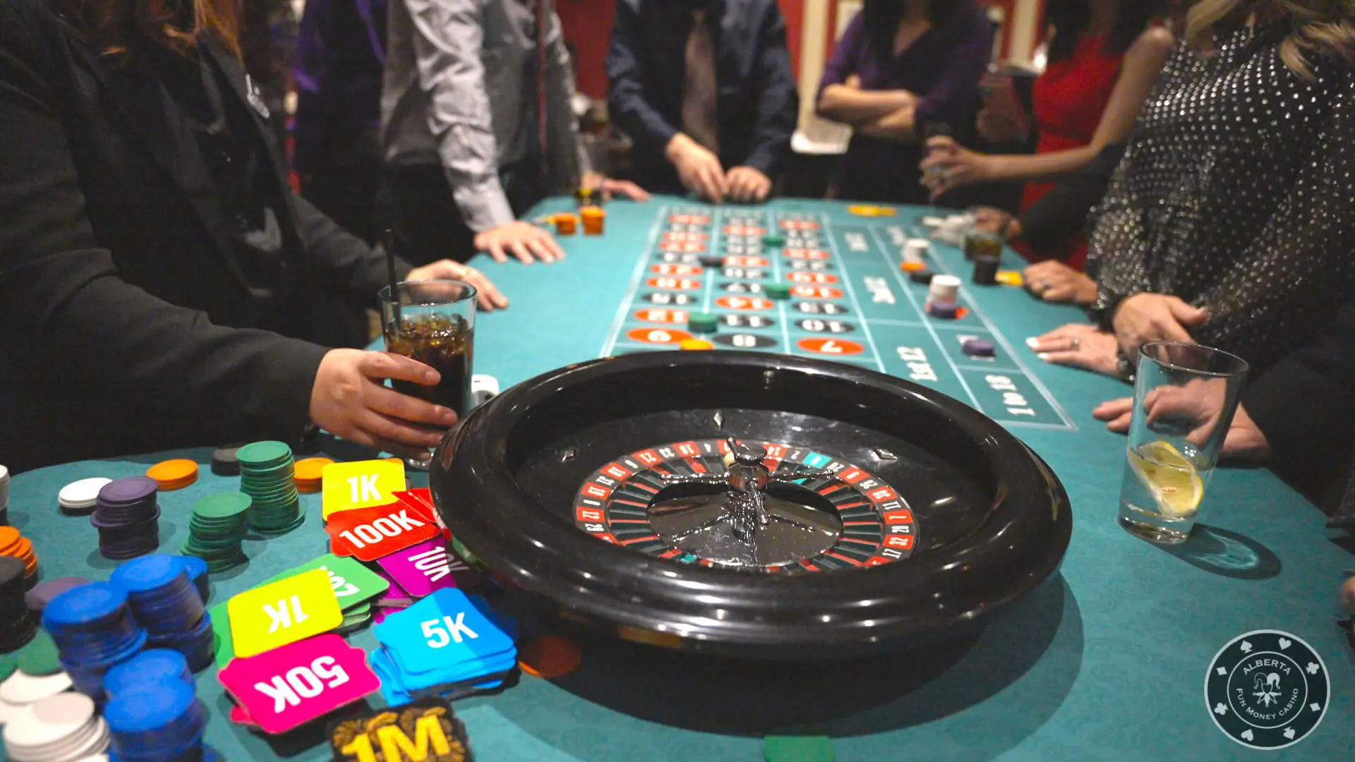 A group of people standing around a roulette table.
