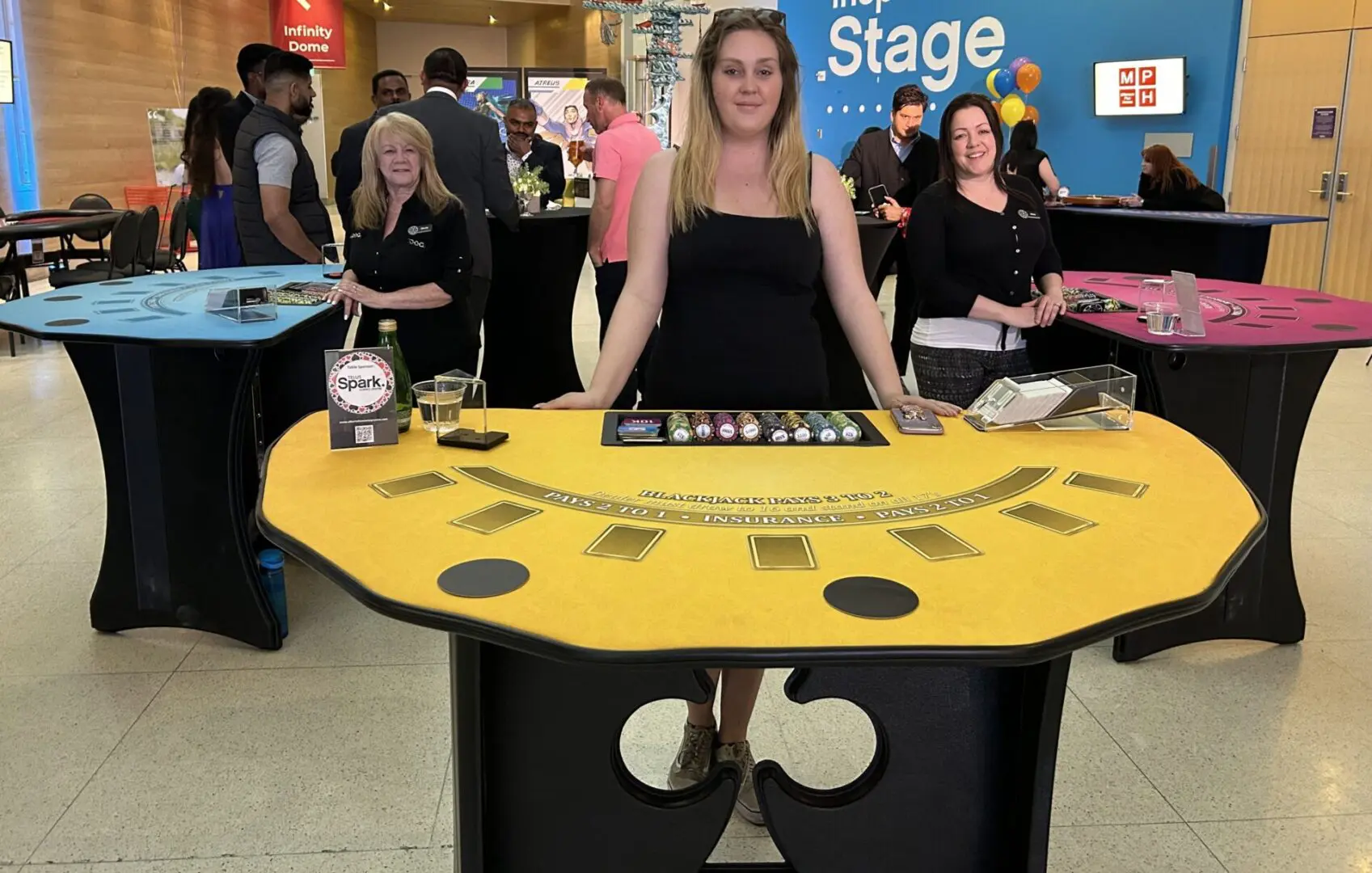 A woman standing behind a table with a roulette wheel on it.
