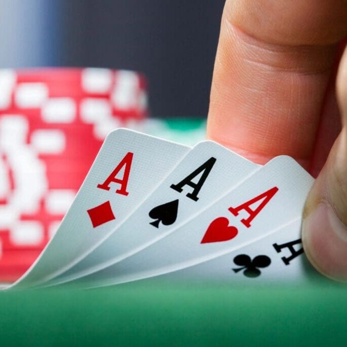 A person holding four aces on top of a green table.